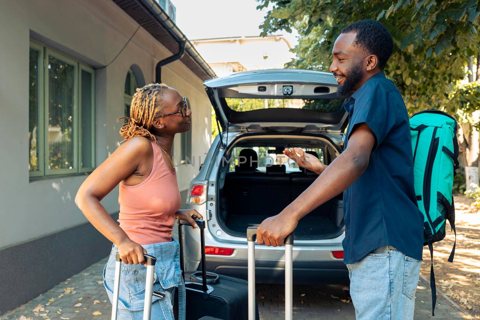 Man and woman in love travelling on holiday, putting travel bags in trunk of automobile. Leaving on vacation trip for recreation. Couple in relationship going on urban adventure with luggage.