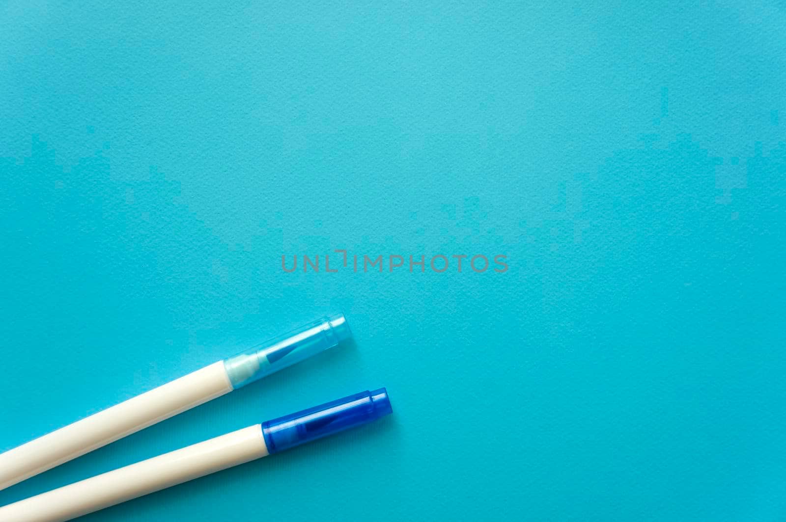The creative concept of creativity is empty. Two felt-tip pens blue and blue lie off the edge of the blue kraft background. Back to school. Medical Notes. In aquamirin tones.
