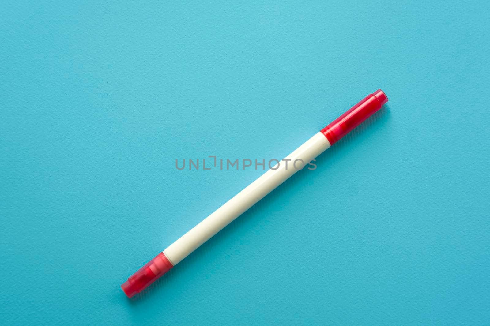 The creative concept of creativity is empty. A single red marker for marking lie off the edge of the blue kraft background. Back to school. Medical Notes. In aquamirin tones.