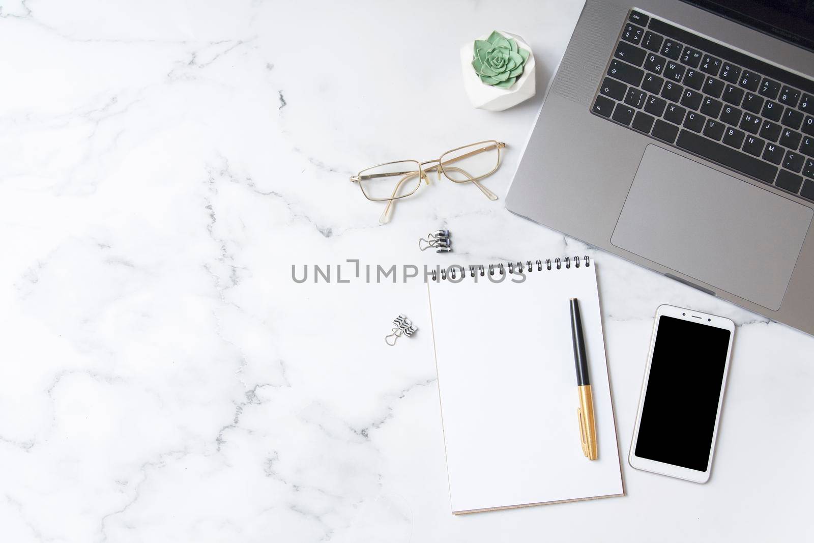 Top view workspace with notebook mock up, smartphone, laptop on marble background with copy space. Business desktop concept