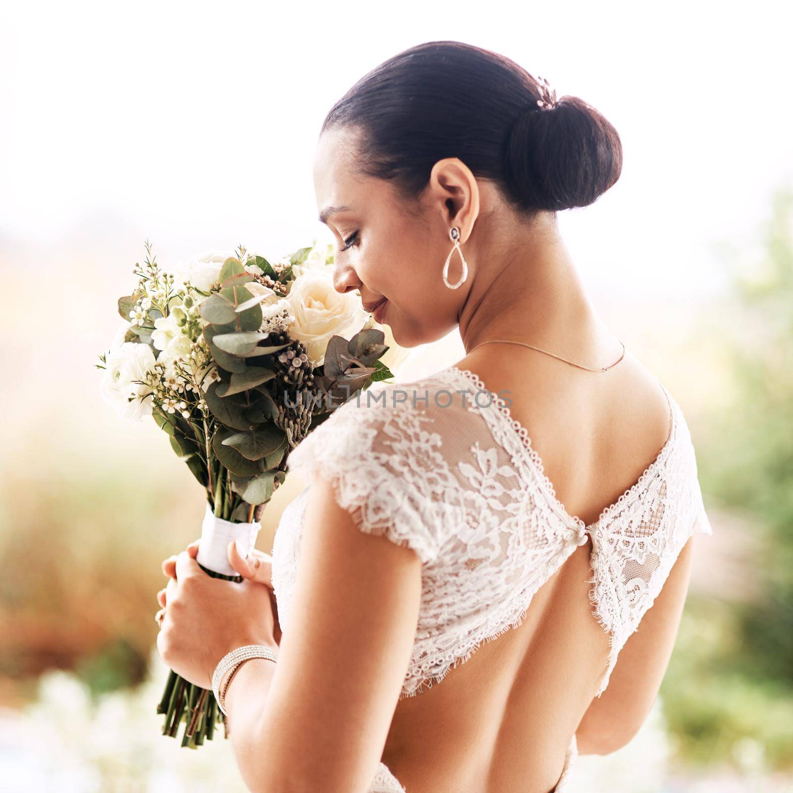 The scent of love. a beautiful young bride smelling her bouquet of flowers outdoors on her wedding day