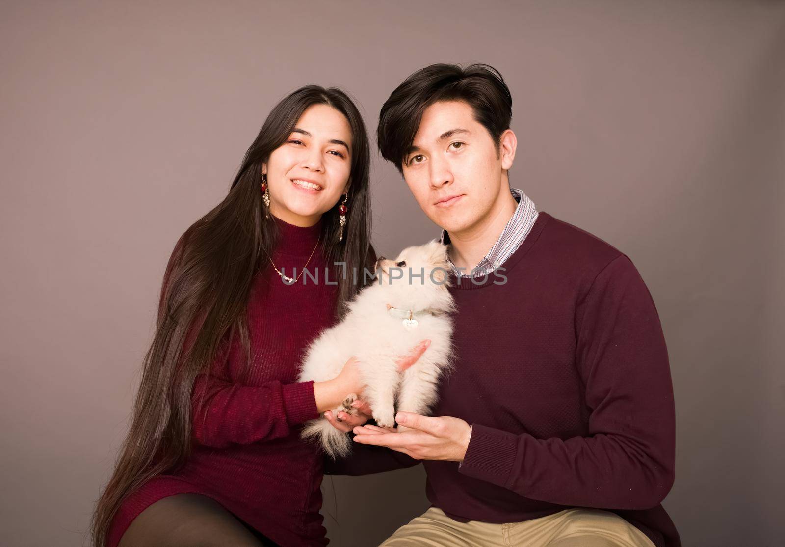 Attractive young biracial couple posing with white Pomeranian puppy by jarenwicklund