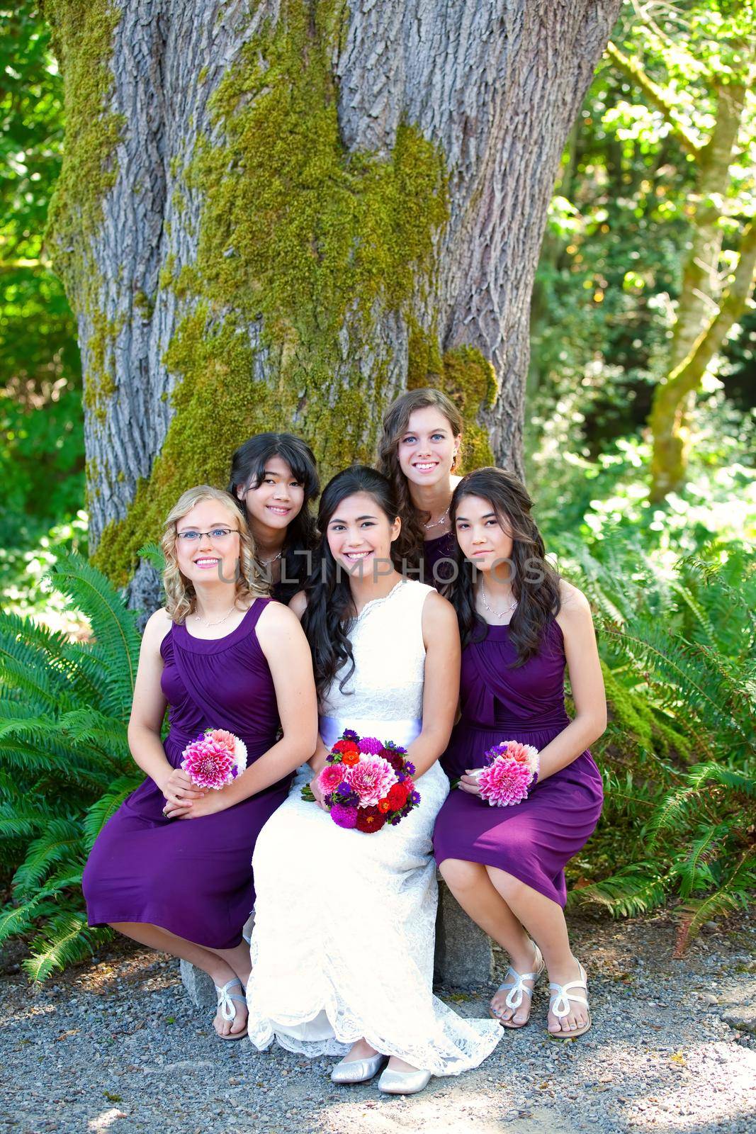 Beautiful biracial young bride smiling with her multiethnic group of bridesmaids by jarenwicklund