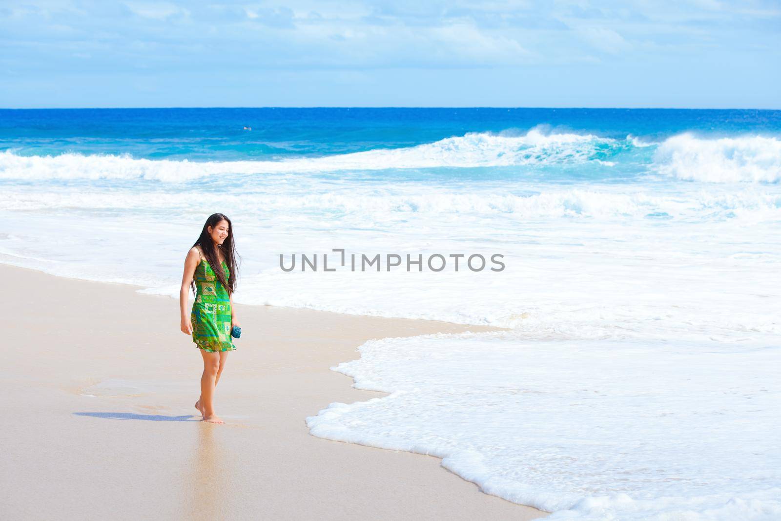 Beautiful teen girl in green dress walking along Hawaiian beach by jarenwicklund