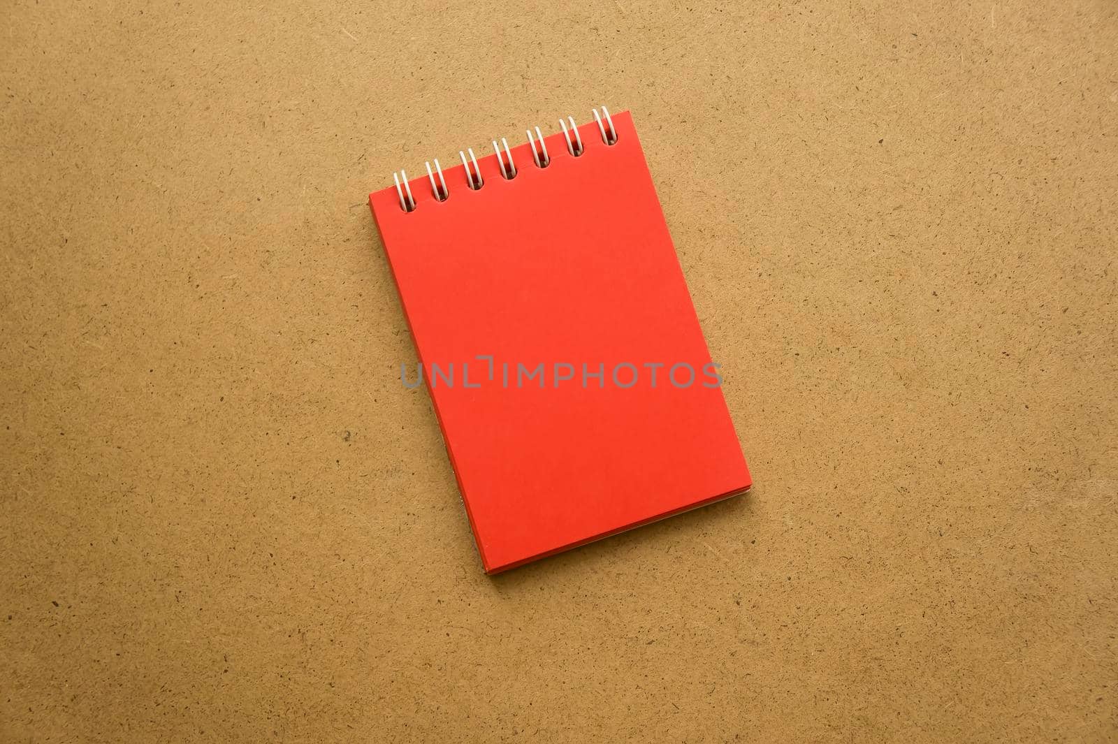 Red notepad for notes with red sheets. Blank space for notes. Mocap. On gray warm ochre kraft background. Holiday calendar notes on notepad. Background for inscriptions. Small notepad with spring. by mr-tigga