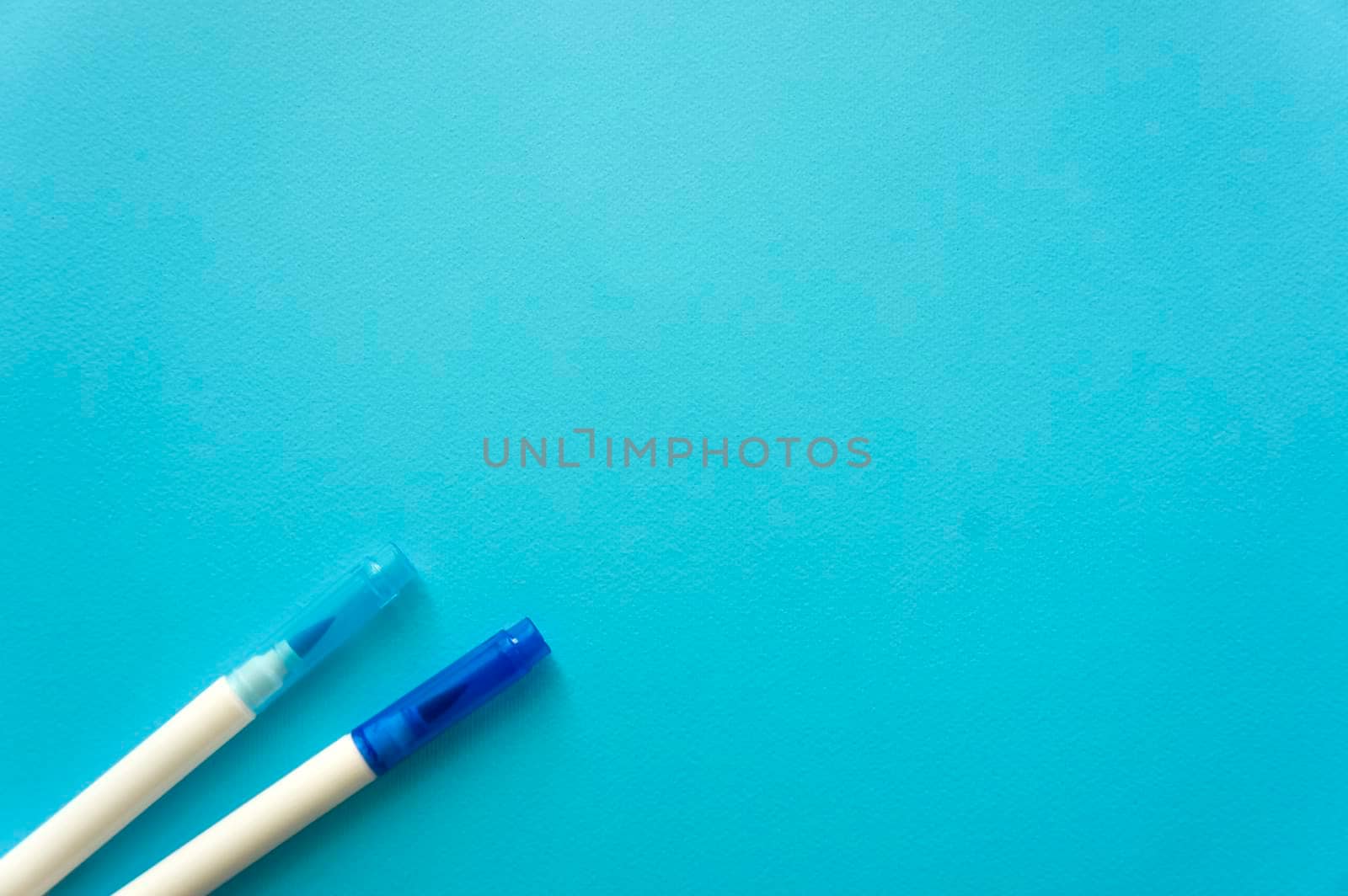 The creative concept of creativity is empty. Two felt-tip pens blue and blue lie off the edge of the blue kraft background. Back to school. Medical Notes. In aquamirin tones.