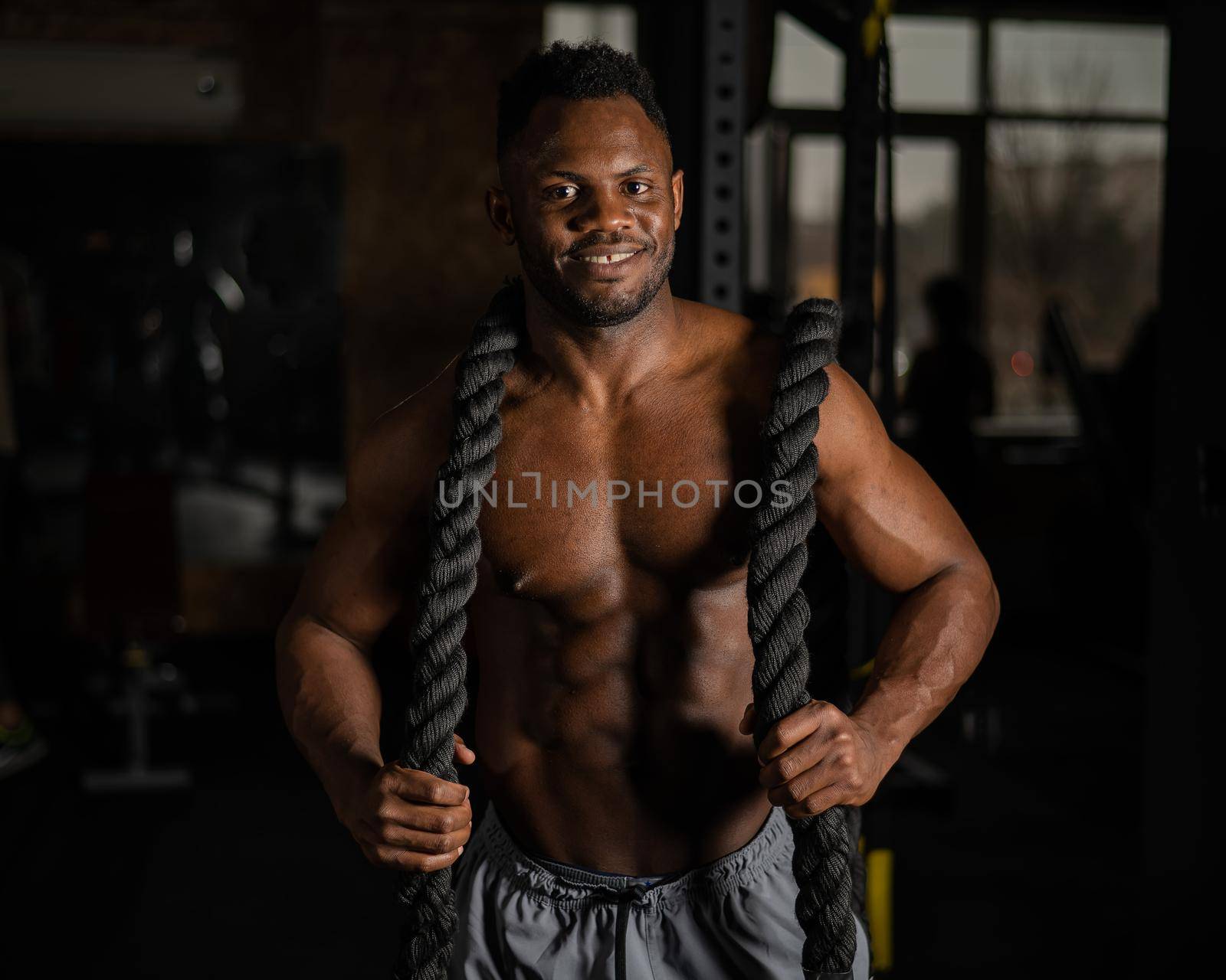 Muscular african american man posing with rope in gym