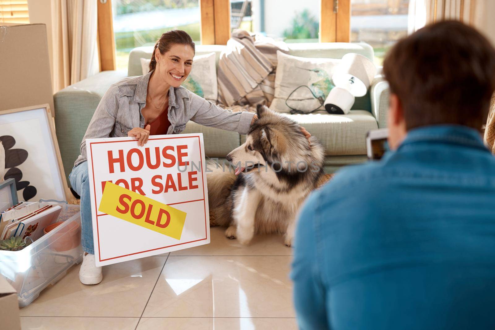 Were the proud owners now. a happy young couple and their dog taking photos with a sold sign in their new home