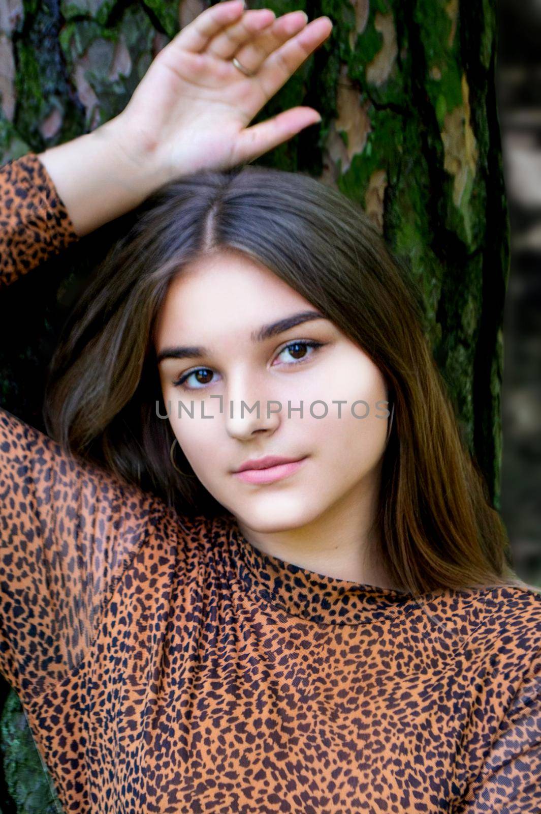 Emotional girl teenager with long hair hairstyle braids in a green shirt sits on a bench in the park. by milastokerpro