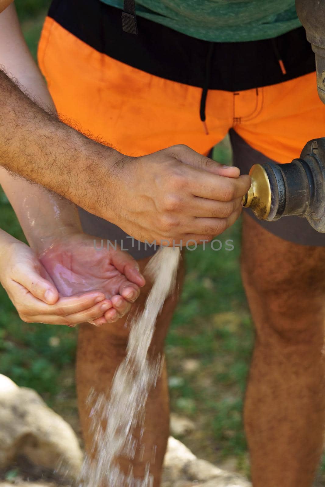 opening the faucet of a fountain and some hands catching water by joseantona