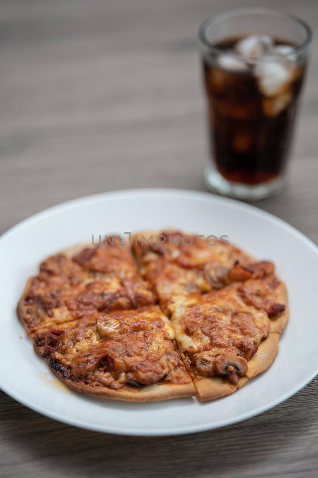 Black burned baked homemade pizza with glass of soft drink.