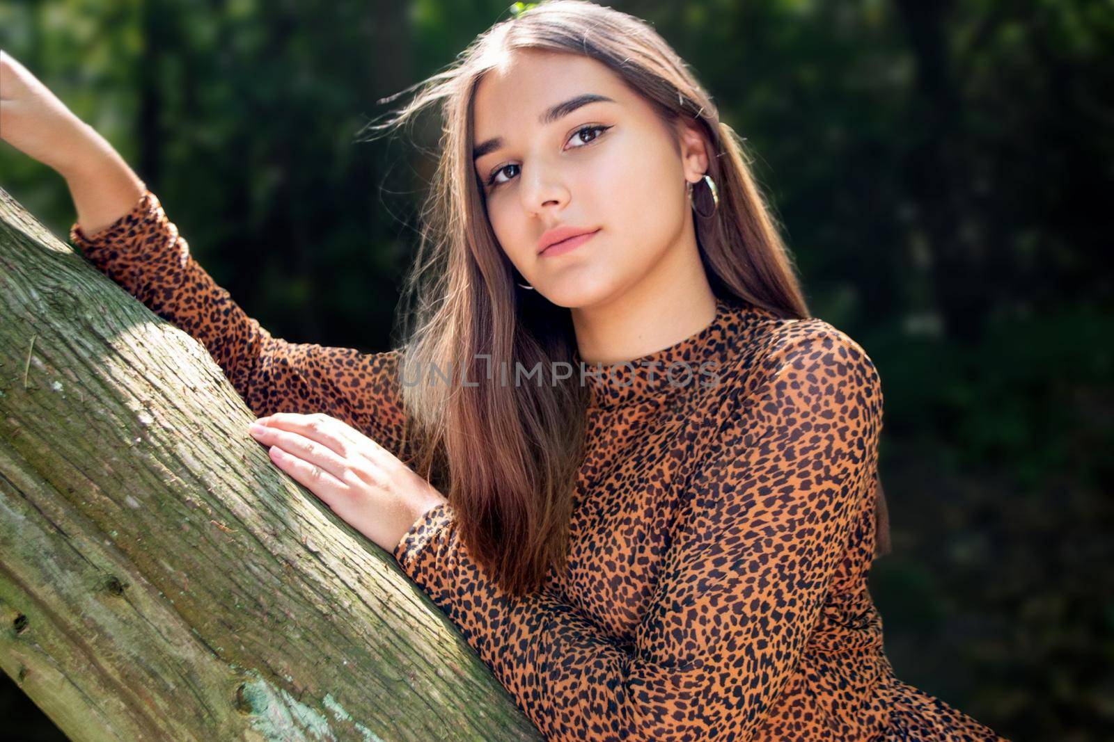 Emotional girl teenager with long hair hairstyle braids in a green shirt sits on a bench in the park. by milastokerpro