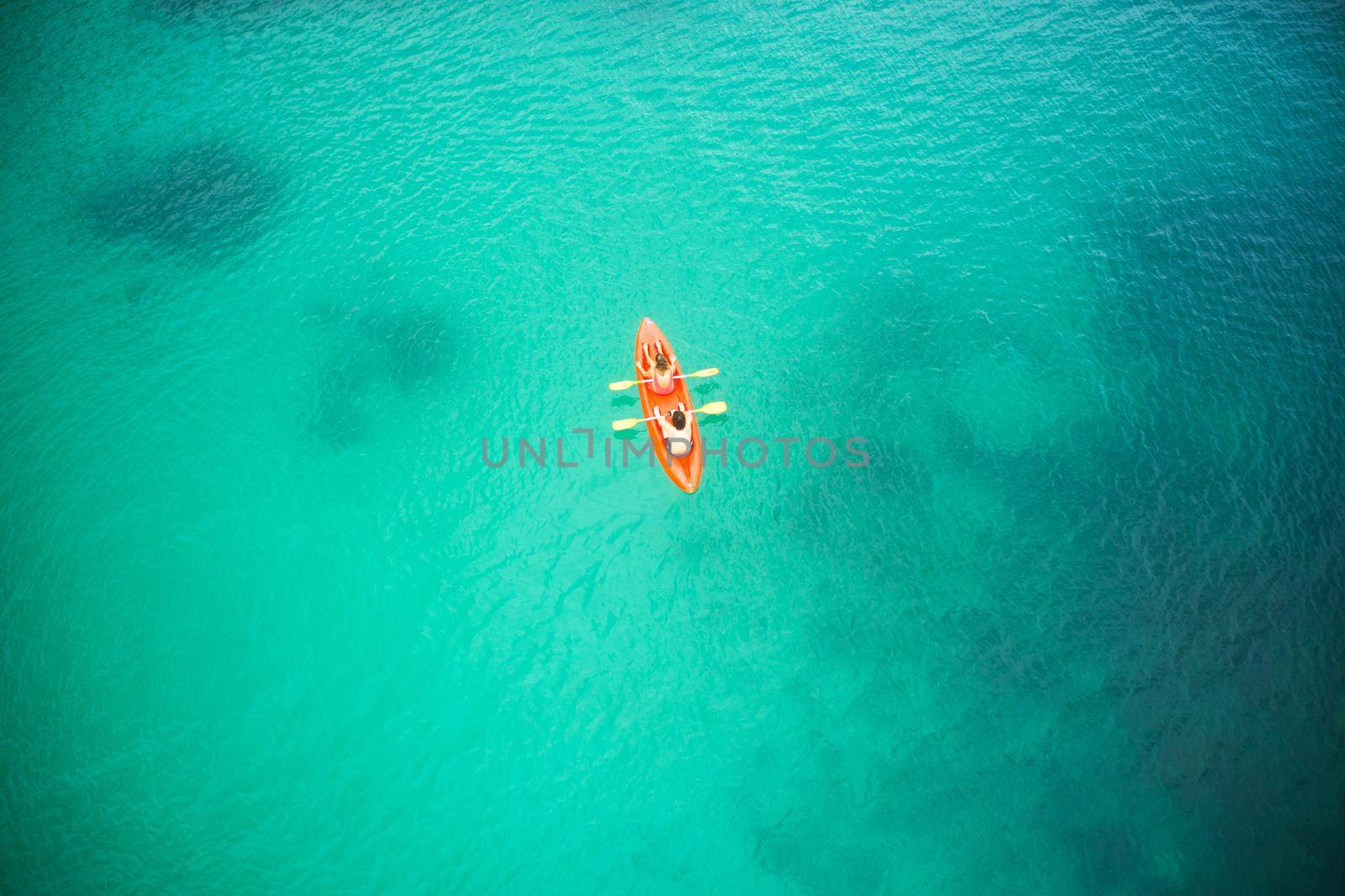 The greatest adventures in life are found out at sea. High angle shot of an adventurous young couple canoeing together in the beautiful oceans of Indonesia. by YuriArcurs