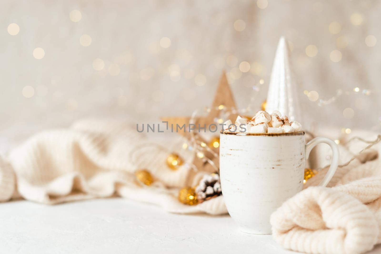Details of Still life, cup of coffee with marshmallows, wooden eco natural decor, Christmas lights with sweater on white background, home decor in cozy house. Winter weekend concept with copy space