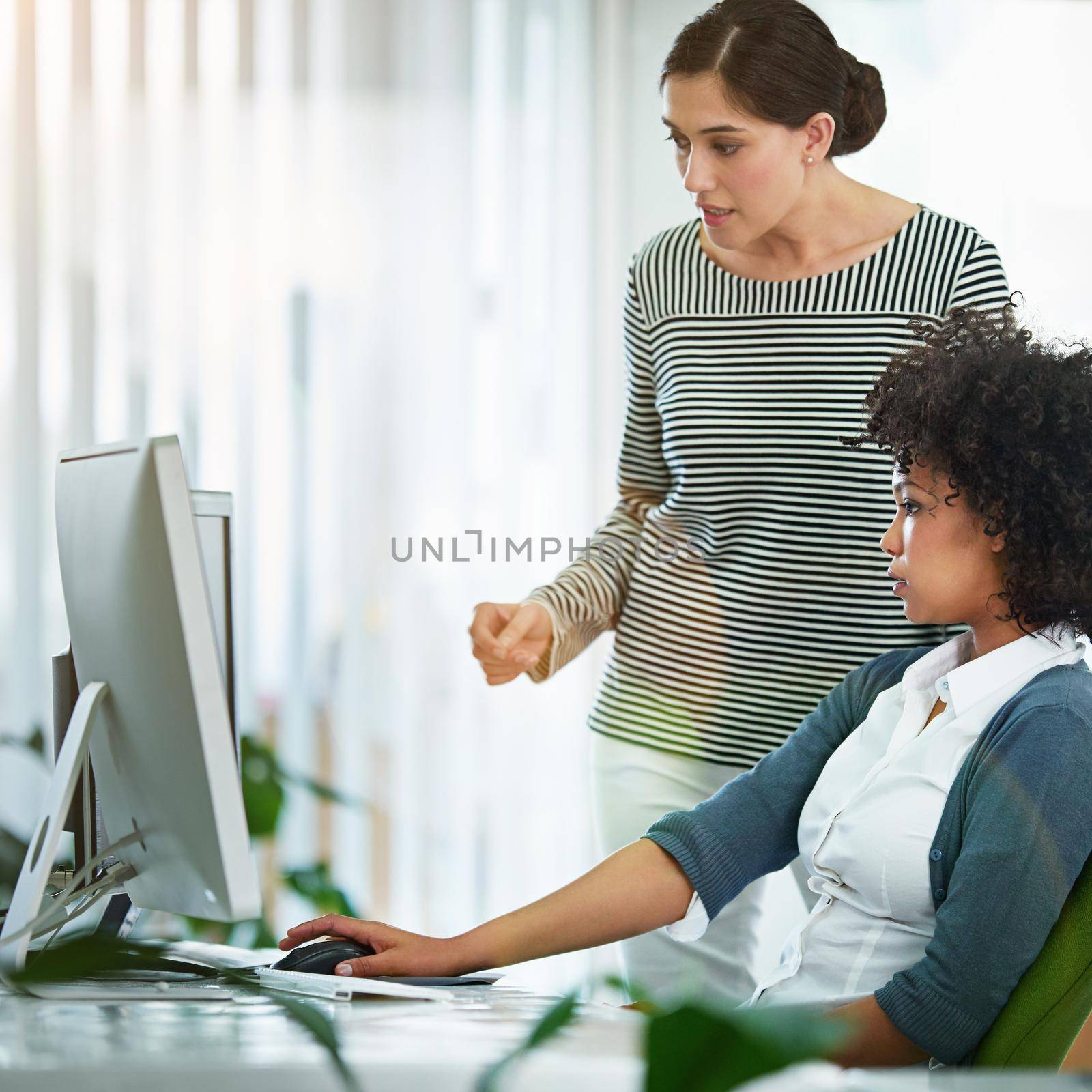A training manager talking about online collaboration project with intern assistant looking on a desktop monitor screen. Business woman discussing latest social media strategy or analyzing seo trends.