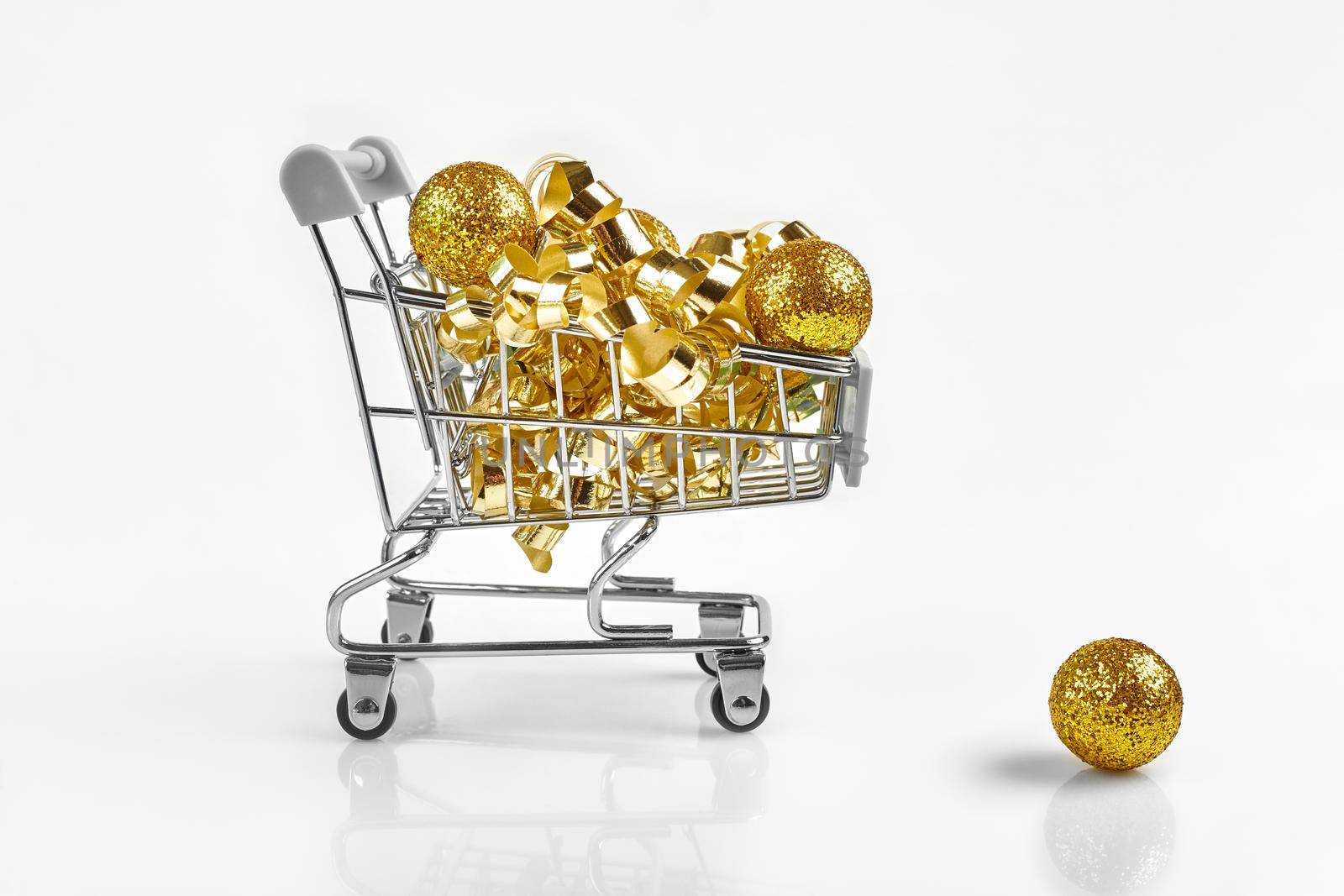 Full of Christmas decoration balls in miniature shopping cart as Christmas and new year season spending concept. White background. Copy space