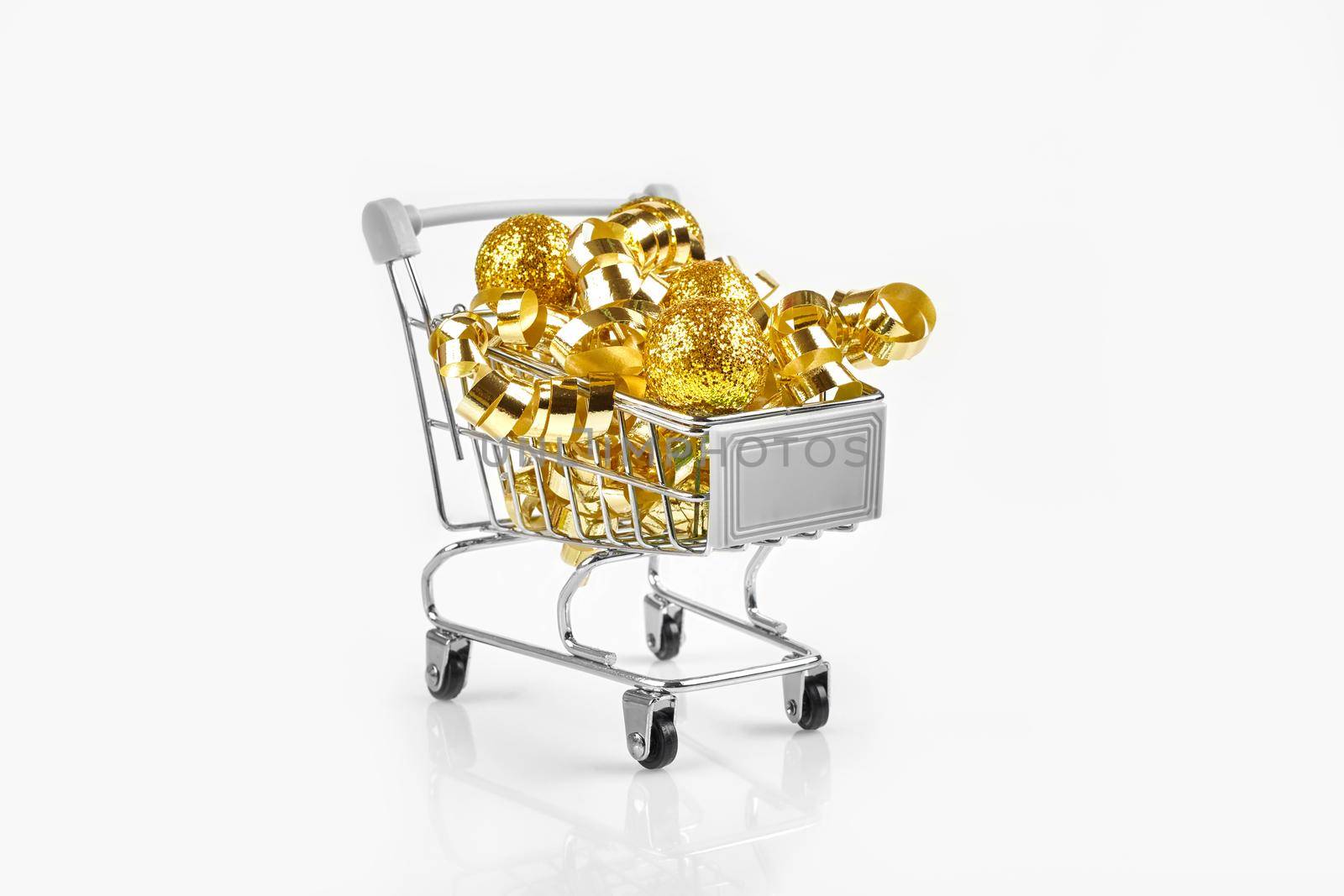 Full of Christmas decoration balls in miniature shopping cart as Christmas and new year season spending concept. White background. Copy space