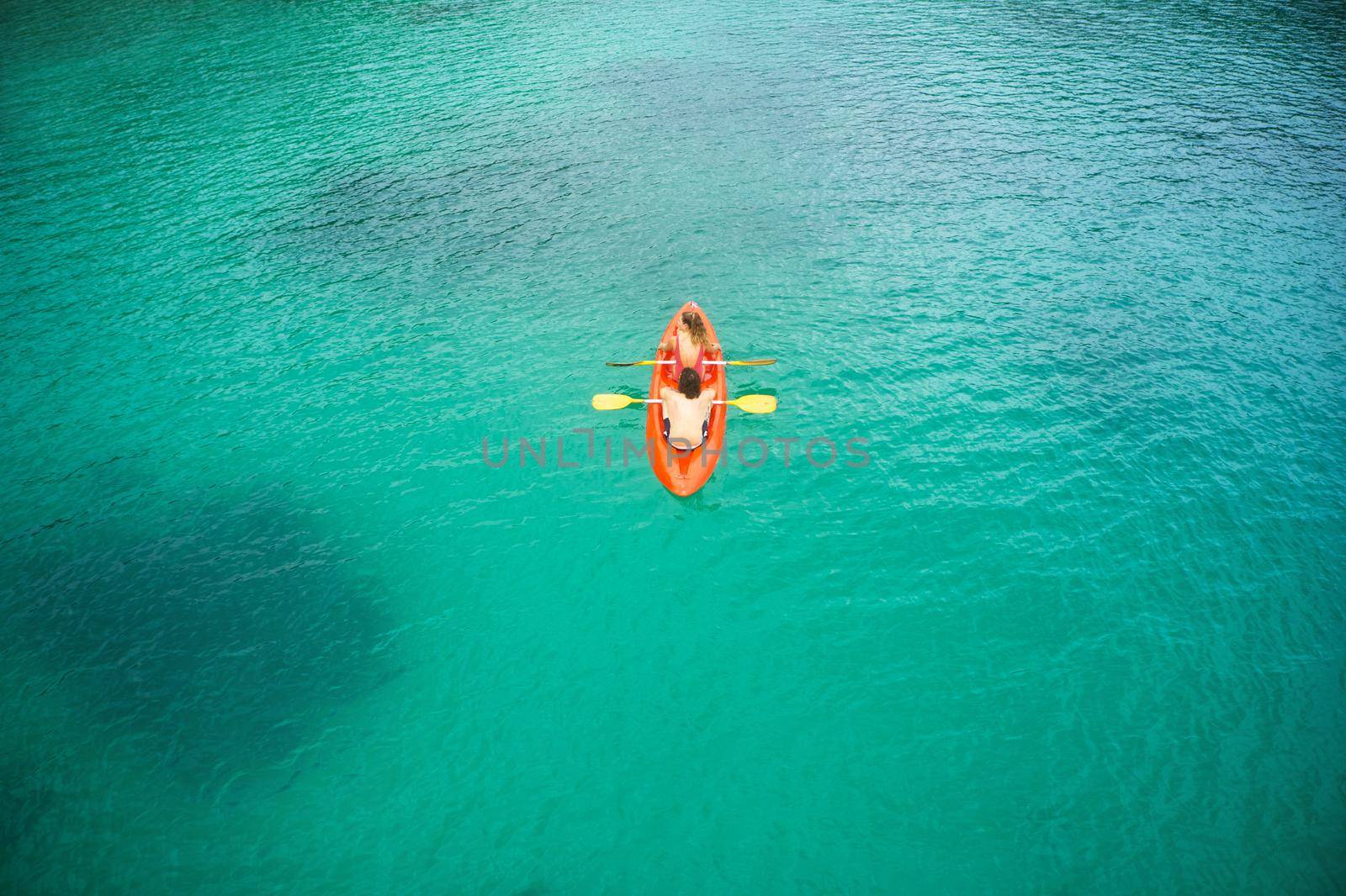 Let go of your fears and embrace the adventure. High angle shot of an adventurous young couple canoeing together in the beautiful oceans of Indonesia. by YuriArcurs