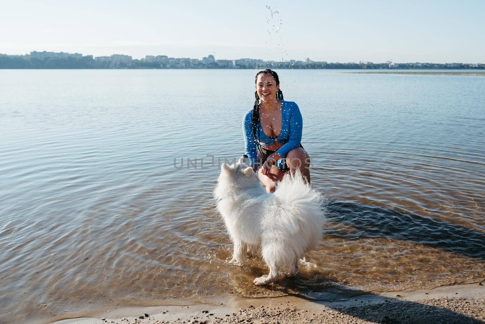 Cheerful Woman Playing with Her Snow-White Dog Breed Japanese Spitz on City Lake