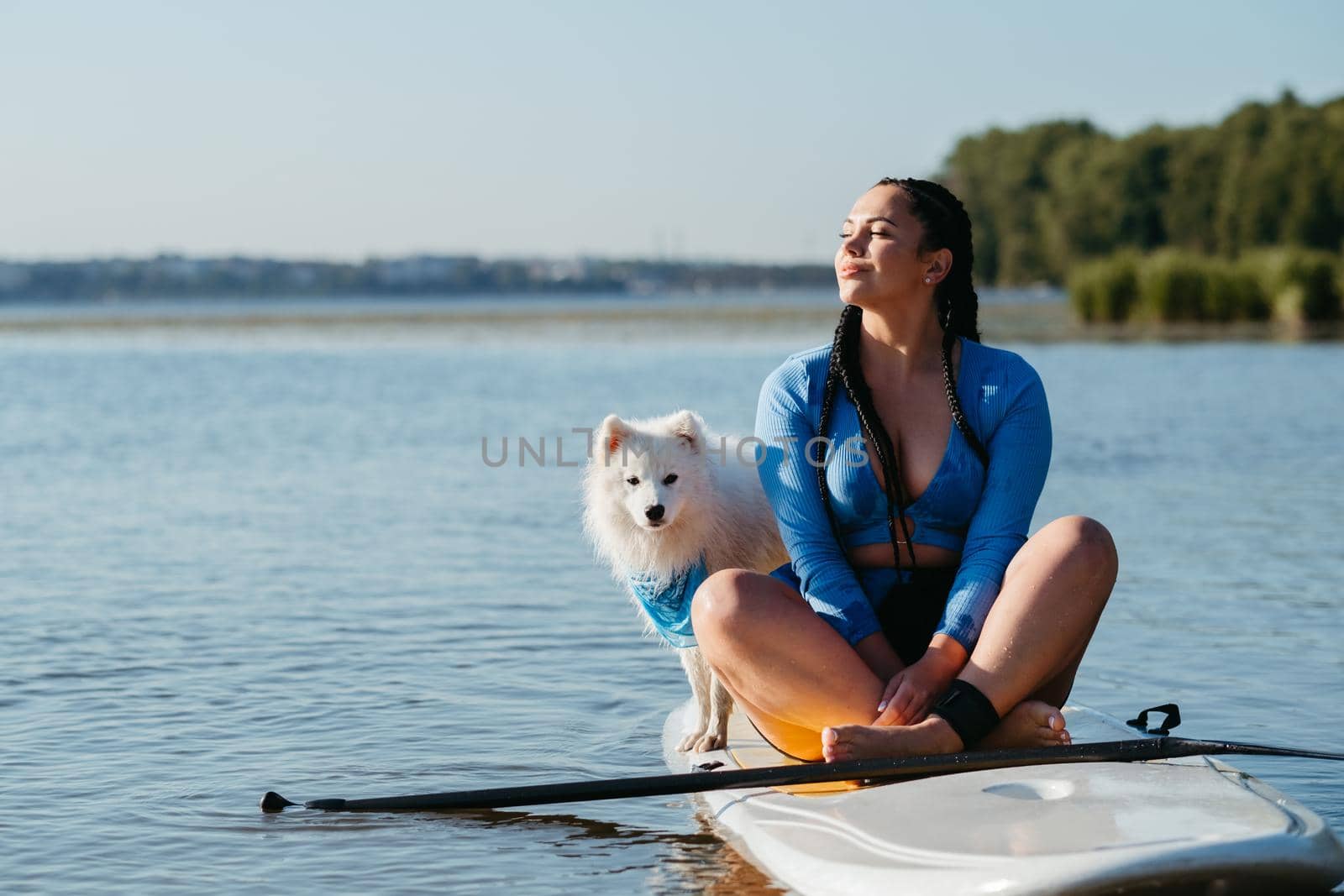 Young Woman Relaxing on the City Lake While Sitting on Sup Board with Her Dog Japanese Spitz