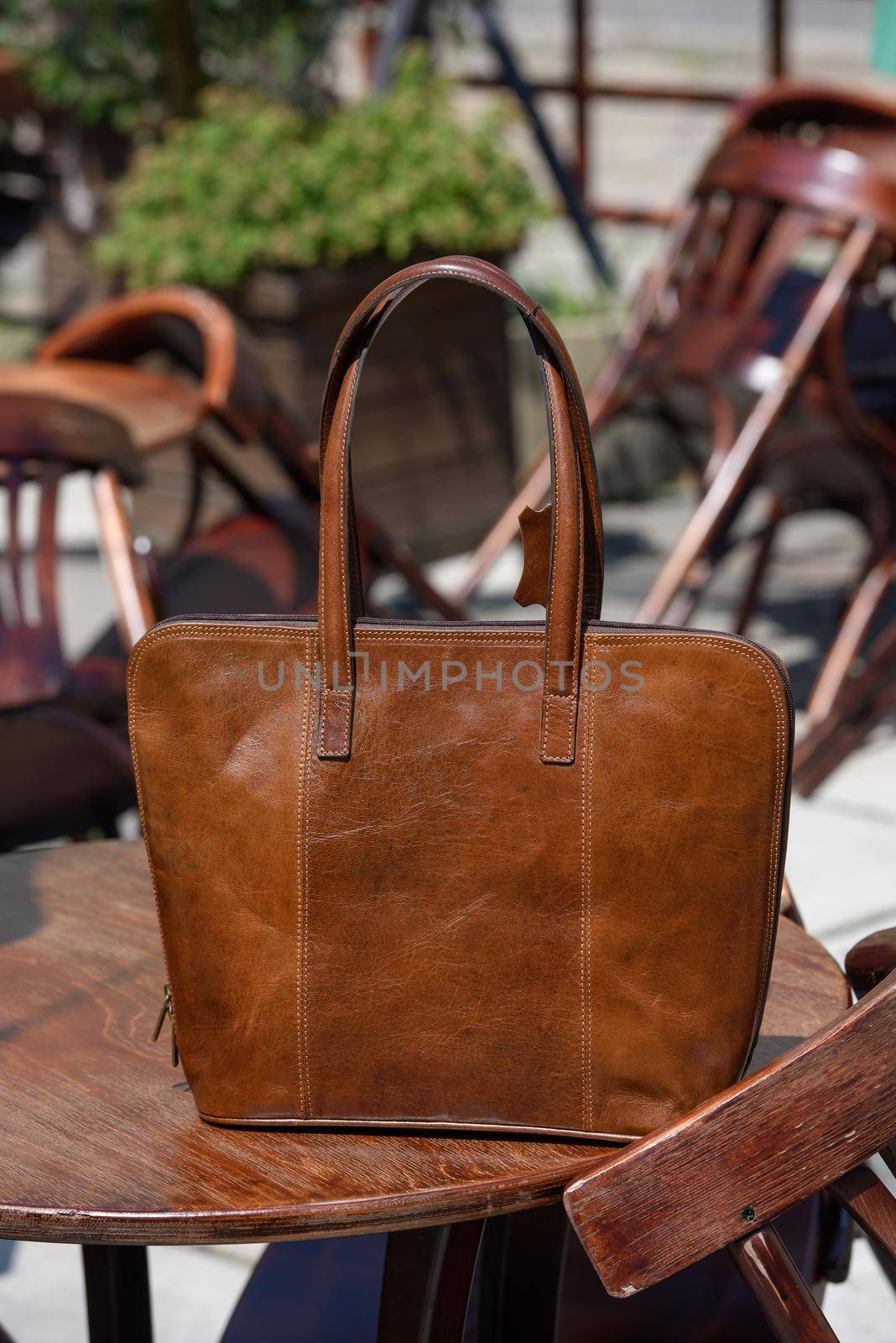 close-up photo of brown leather bag on a wooden table. outdoors photo