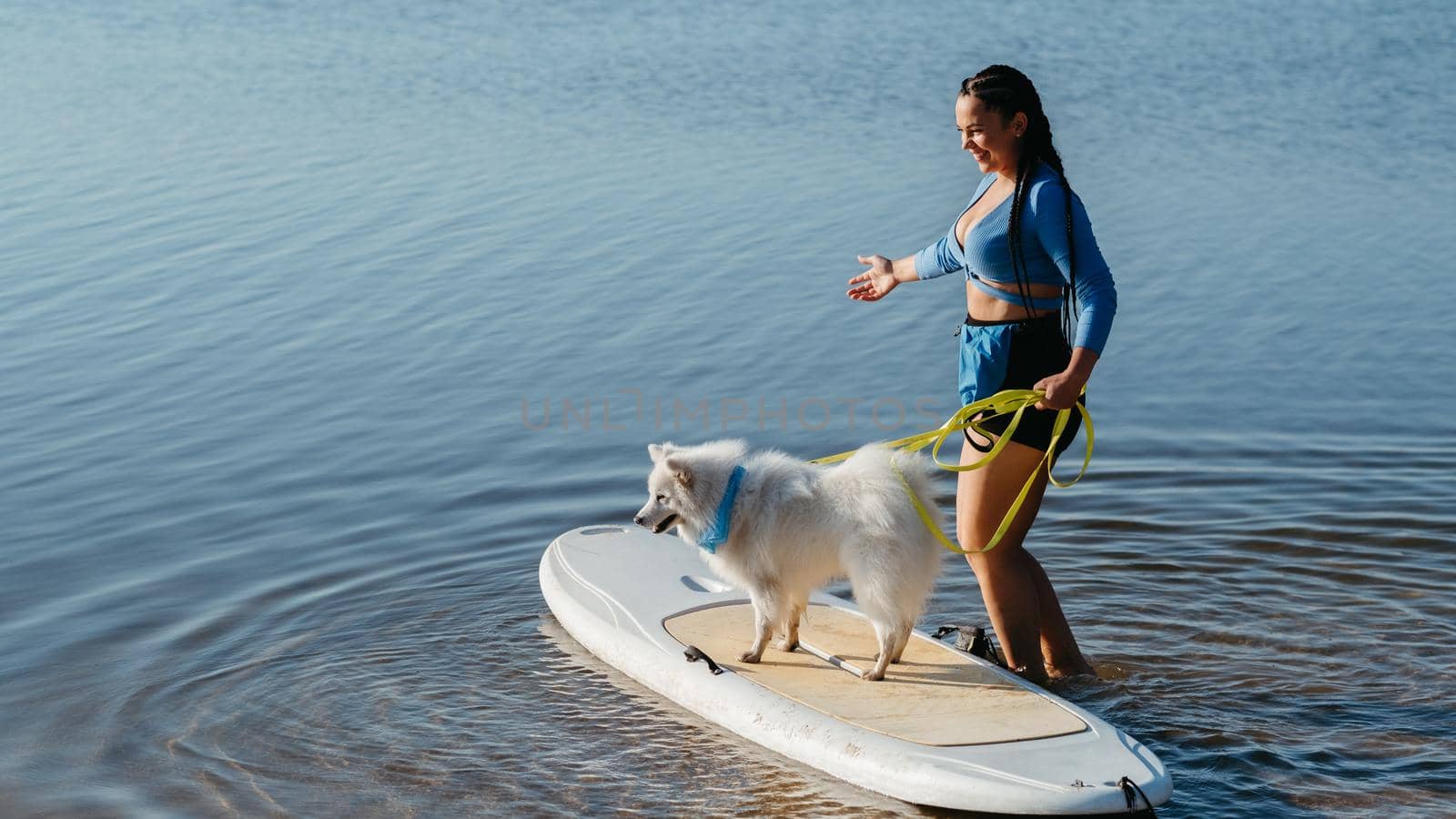 Woman Preparing to Paddleboarding with Her Dog Japanese Spitz Sitting on Sup Board on Lake