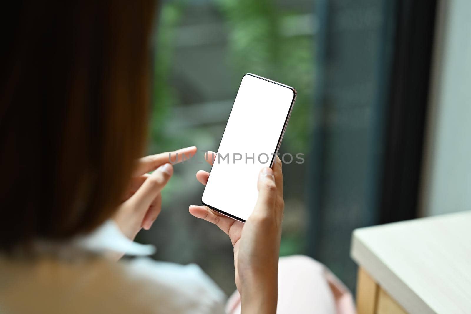 View over shoulder young woman holding mobile phone. Blank display for your advertise text.