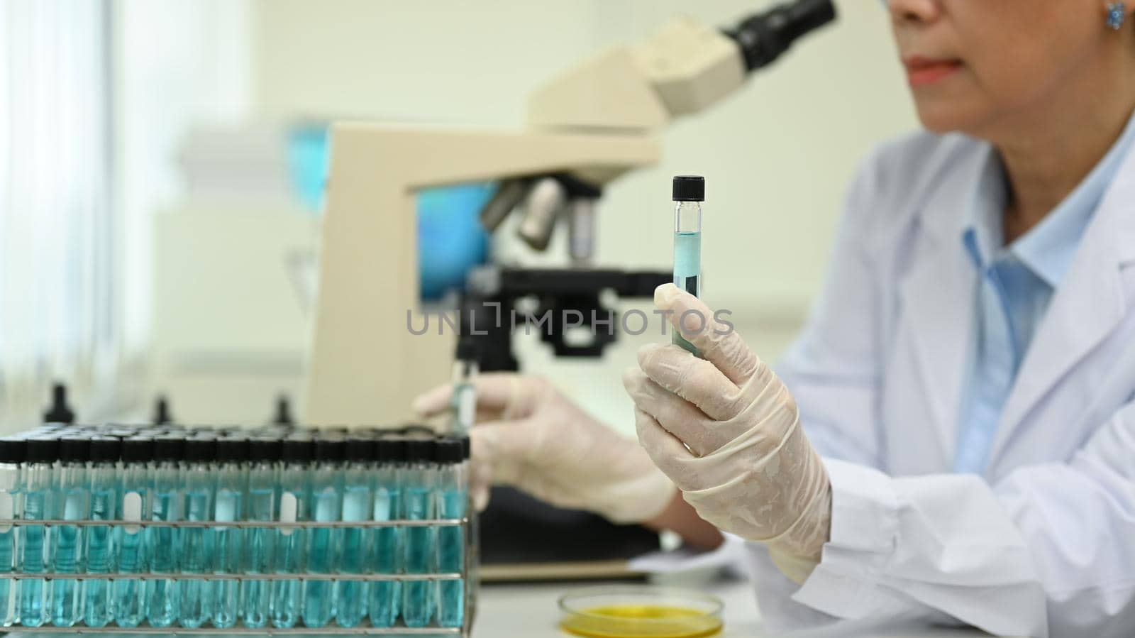 Professional mature female scientist examining samples and liquid in laboratory. Medicine and science researching concepts by prathanchorruangsak