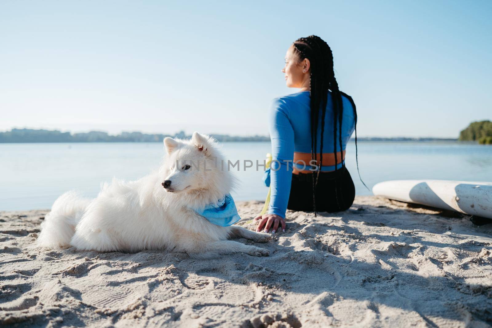 Woman with Locs Sitting on Beach of City Lake with Her Best Friend, Snow-White Dog Breed Japanese Spitz