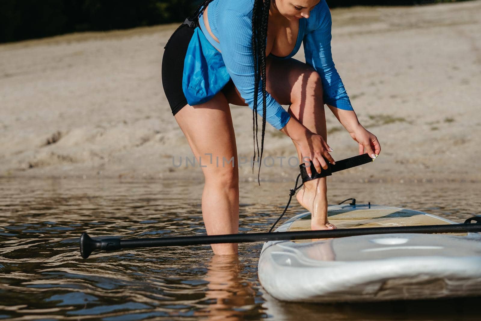 Woman Attaching Insurance Cable of Sup to Her Leg, Preparing to Swim on Board