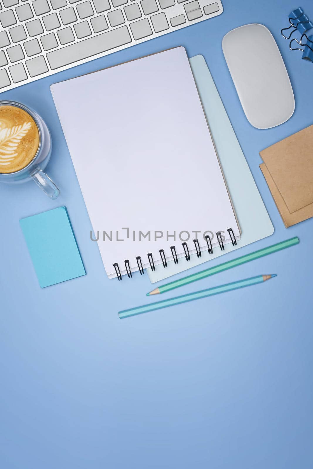 Empty notepad, coffee cup and sticky notes on blue background. by prathanchorruangsak