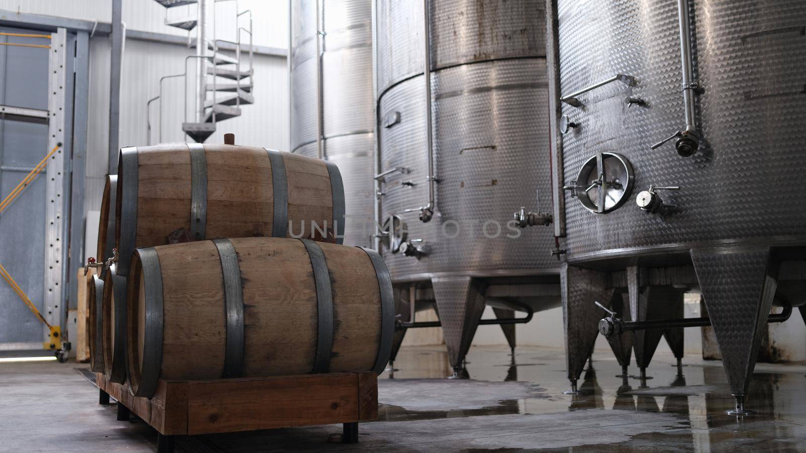 Huge tanks in wine cellars and wooden barrels of wine or alcohol. Production of elite collection wine concept