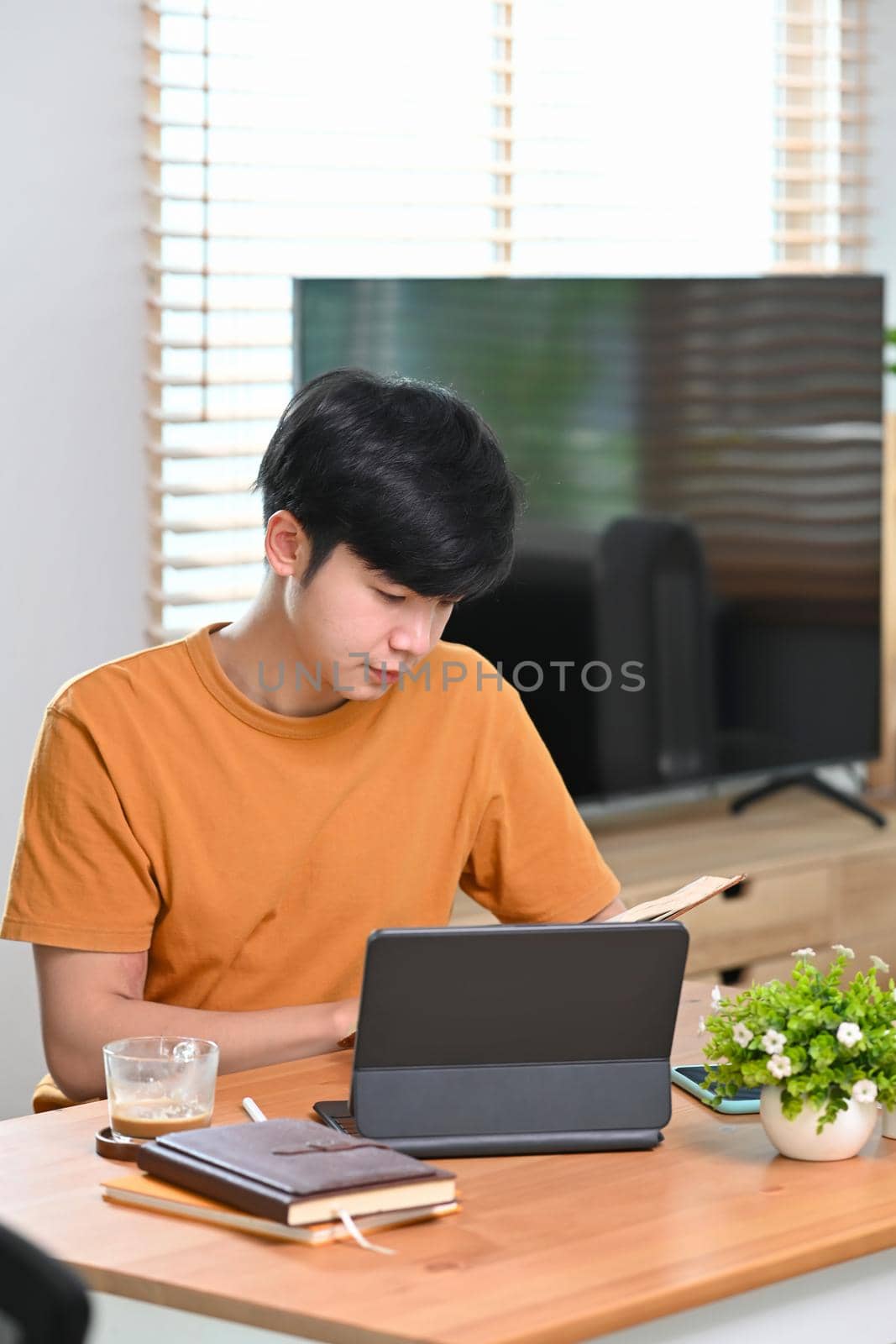 Young man reading book while sitting in living room.
