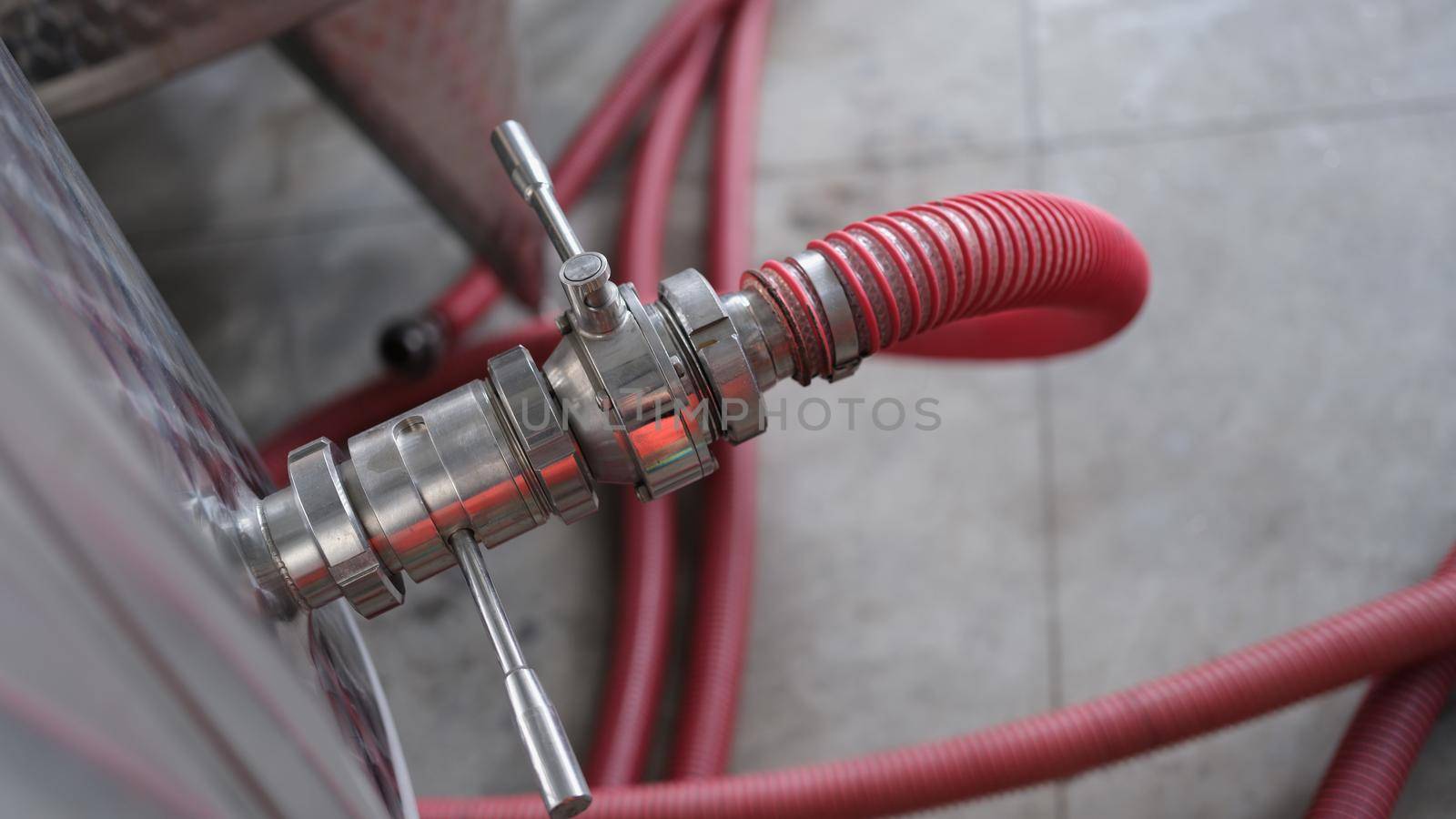 Industrial stainless steel pipe equipment with faucet and hose in wine production or chemical pharmaceutical production. Tank in pharmaceutical industry or chemical plant