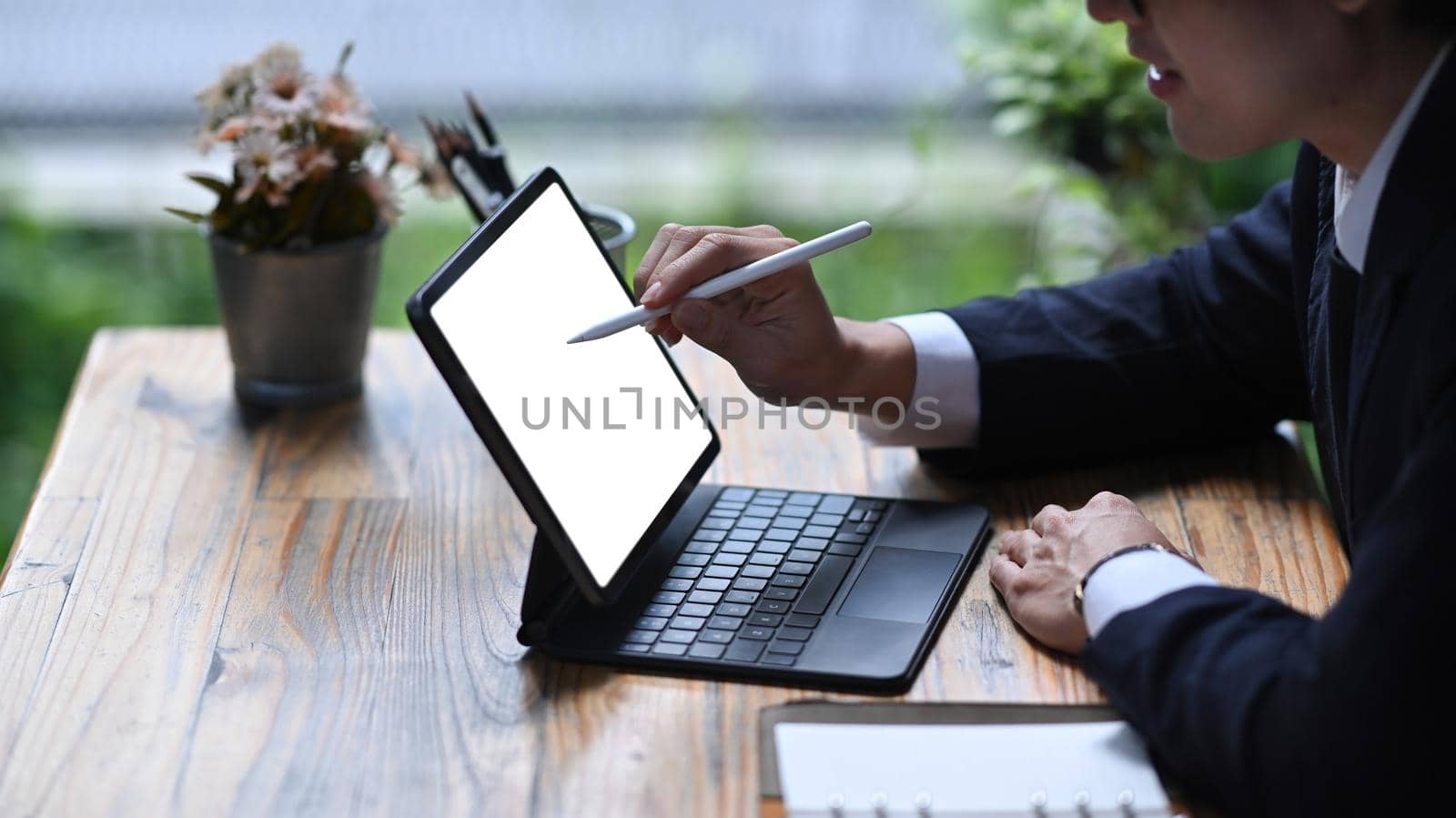 Cropped shot businessman holding stylus pen and writing on digital tablet screen. by prathanchorruangsak