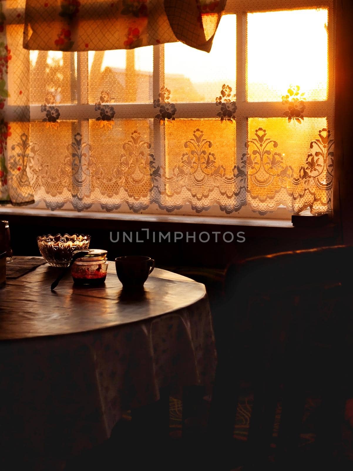 Dining room of veranda in summer house in sunset, country home of countryside in golden hour, cozy still life of rustic mood with light backlight from window and dark shadows of twilight