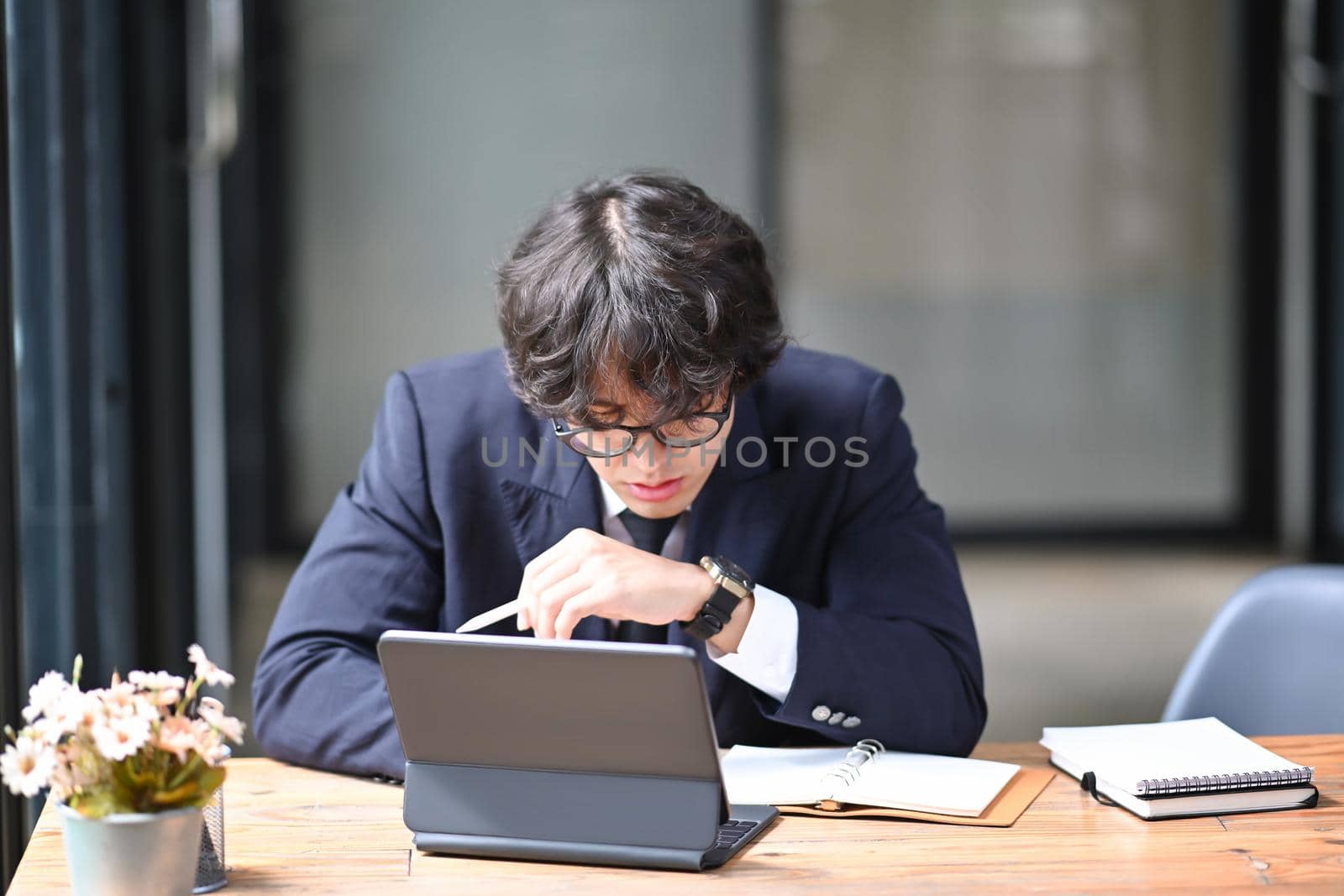 Young businessman working with computer tablet in bright office. by prathanchorruangsak