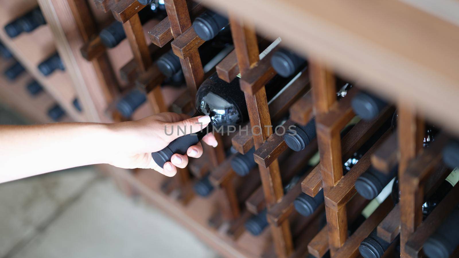 Woman chooses bottle of wine in cellar closeup. Expensive collectible red wines concept