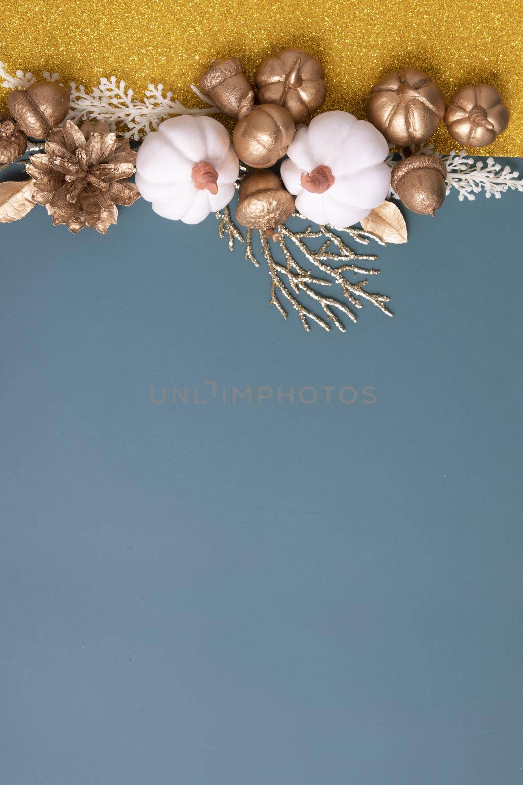 Minimalistic autumn flat lay with copy space and golden acorns, cones, leaves and pumpkins on an colorful background with copy space vertical format