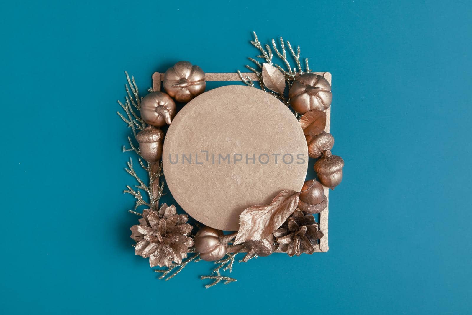 Still life of golden acorns, cones, leaves and pumpkins on a turquoise background with a pedestal. Minimalistic autumn concept with copy space