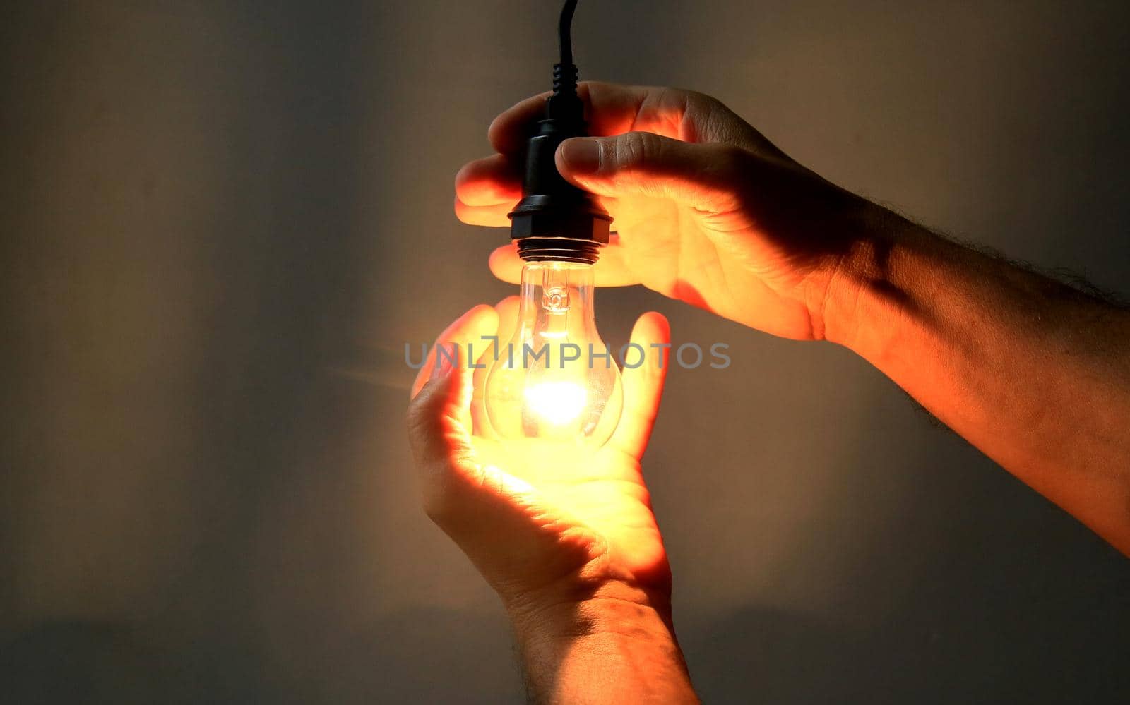 salvador, bahia / brazil - may 17, 2020: hands hold incandescent lamp lit in residence in the city of Salvador.