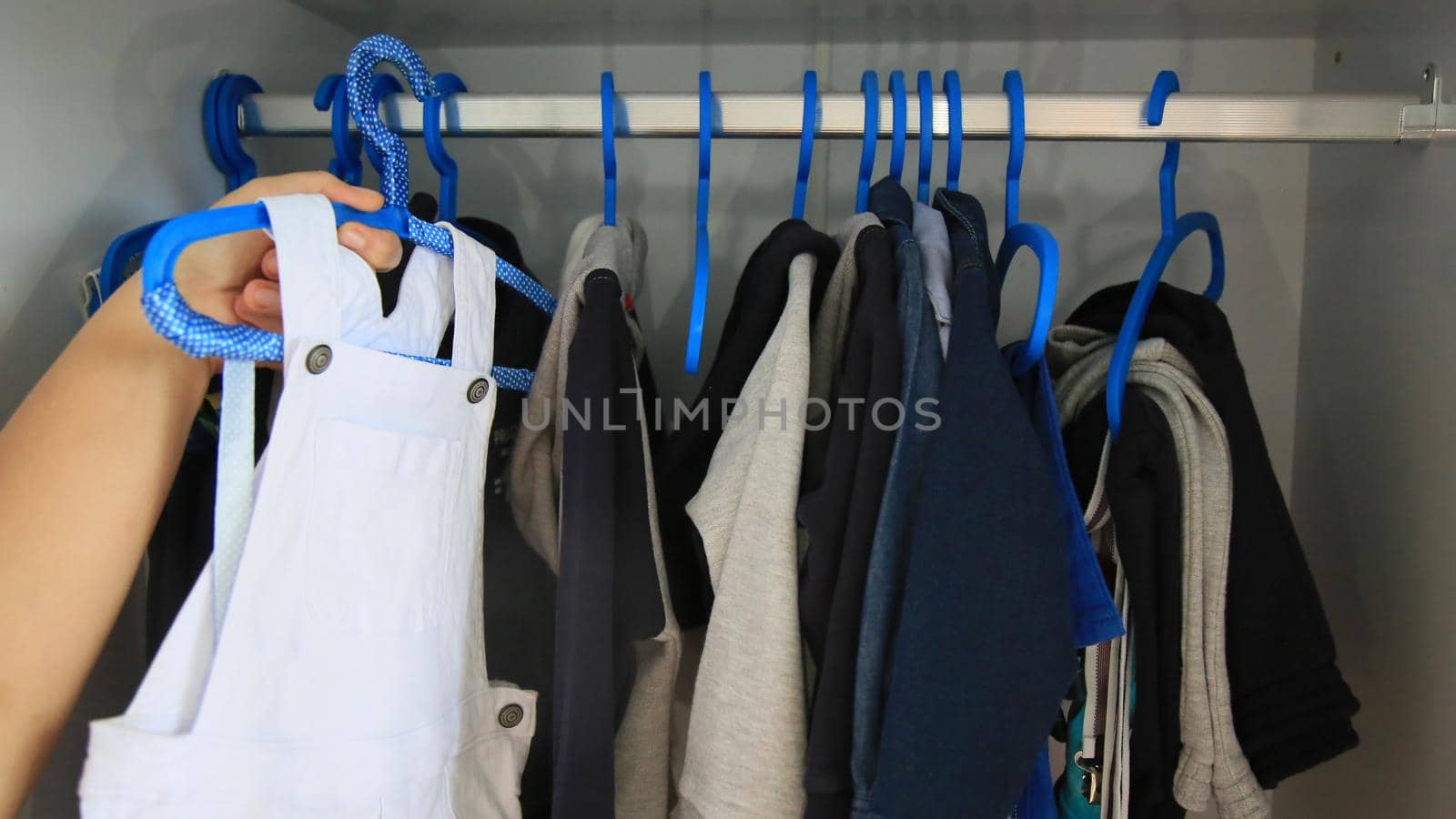 salvador, bahia / brazil - may 7, 2020: hands are seen picking up children's clothes on a hanger.