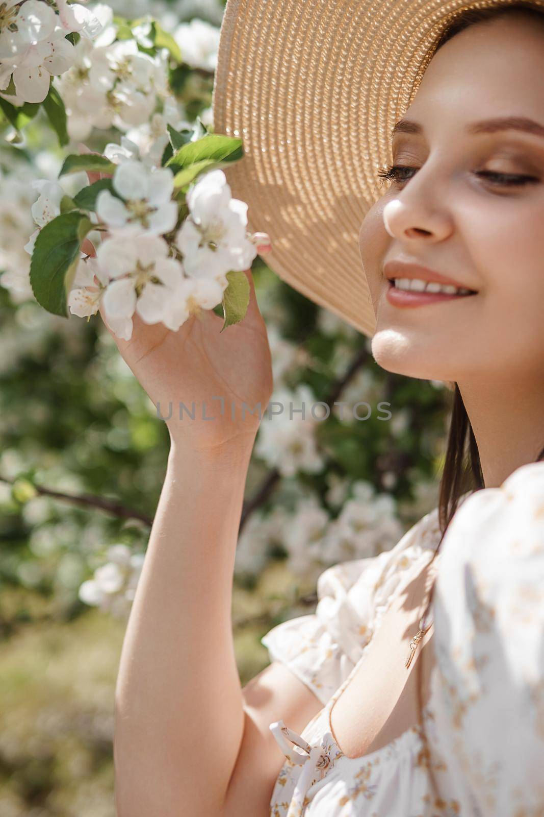 An attractive long-haired woman walks in the spring in the park of blooming apple trees. Spring portrait of a woman