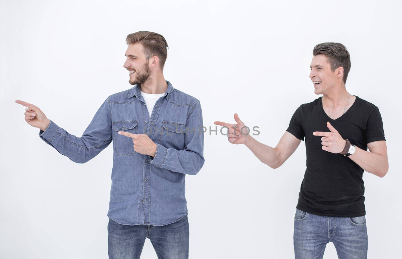 Look there! Happy young people in jeans pointing away, standing on white background
