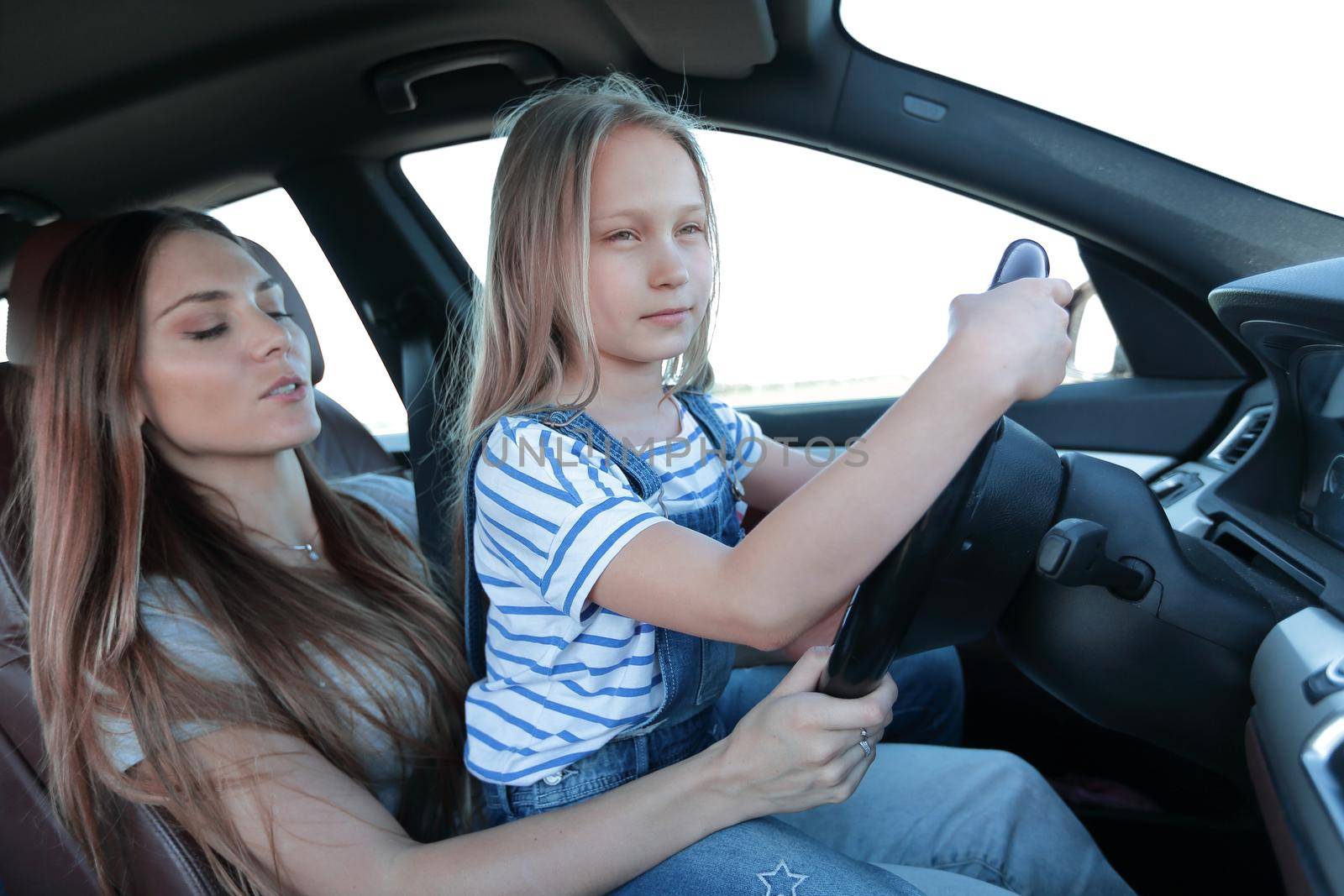 mom and her daughter sitting at the wheel of a car.the concept of parenting