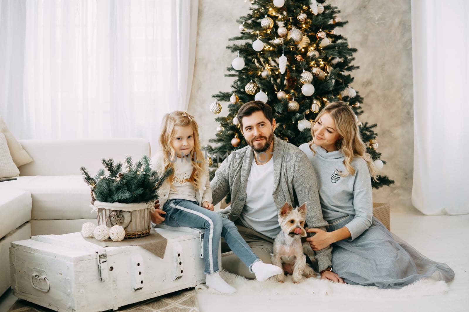 Happy family: mom, dad and pet. Family in a bright New Year's interior with a Christmas tree by Annu1tochka