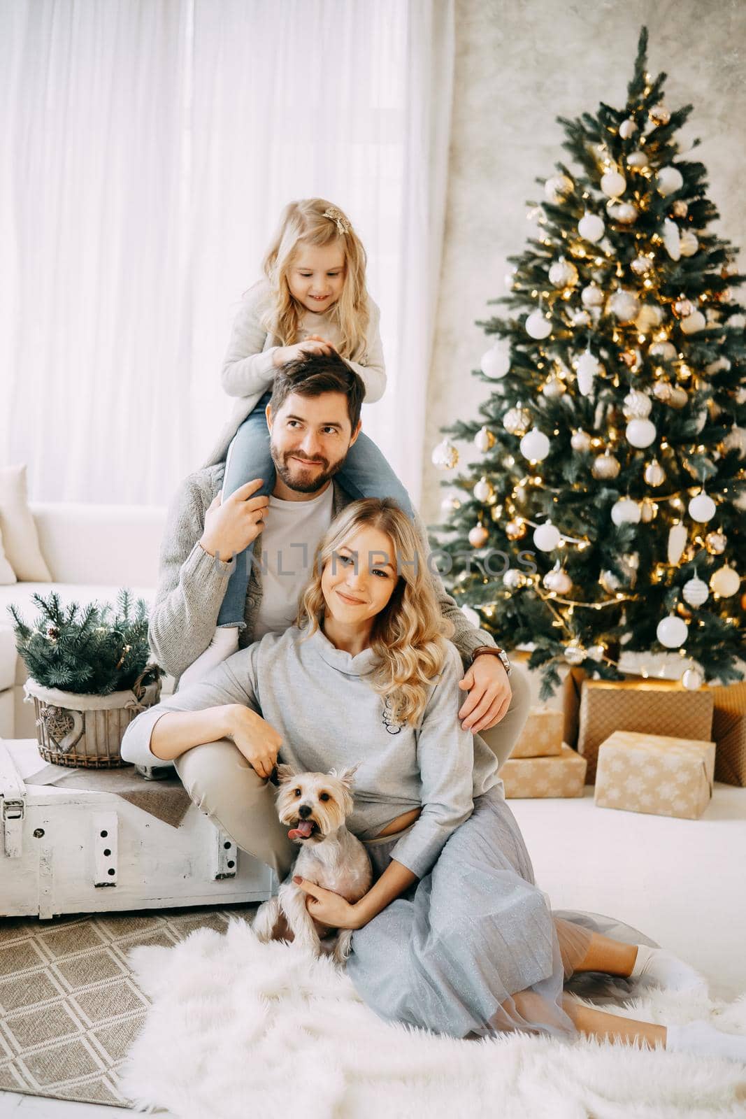 Happy family: mom, dad and pet. Family in a bright New Year's interior with a Christmas tree.