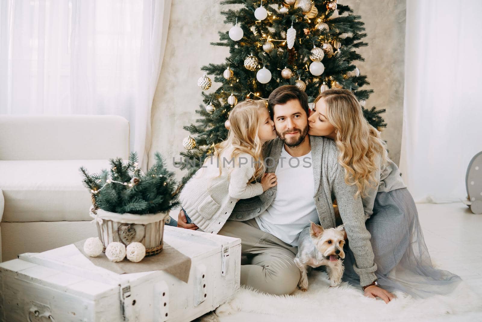 Happy family: mom, dad and pet. Family in a bright New Year's interior with a Christmas tree.