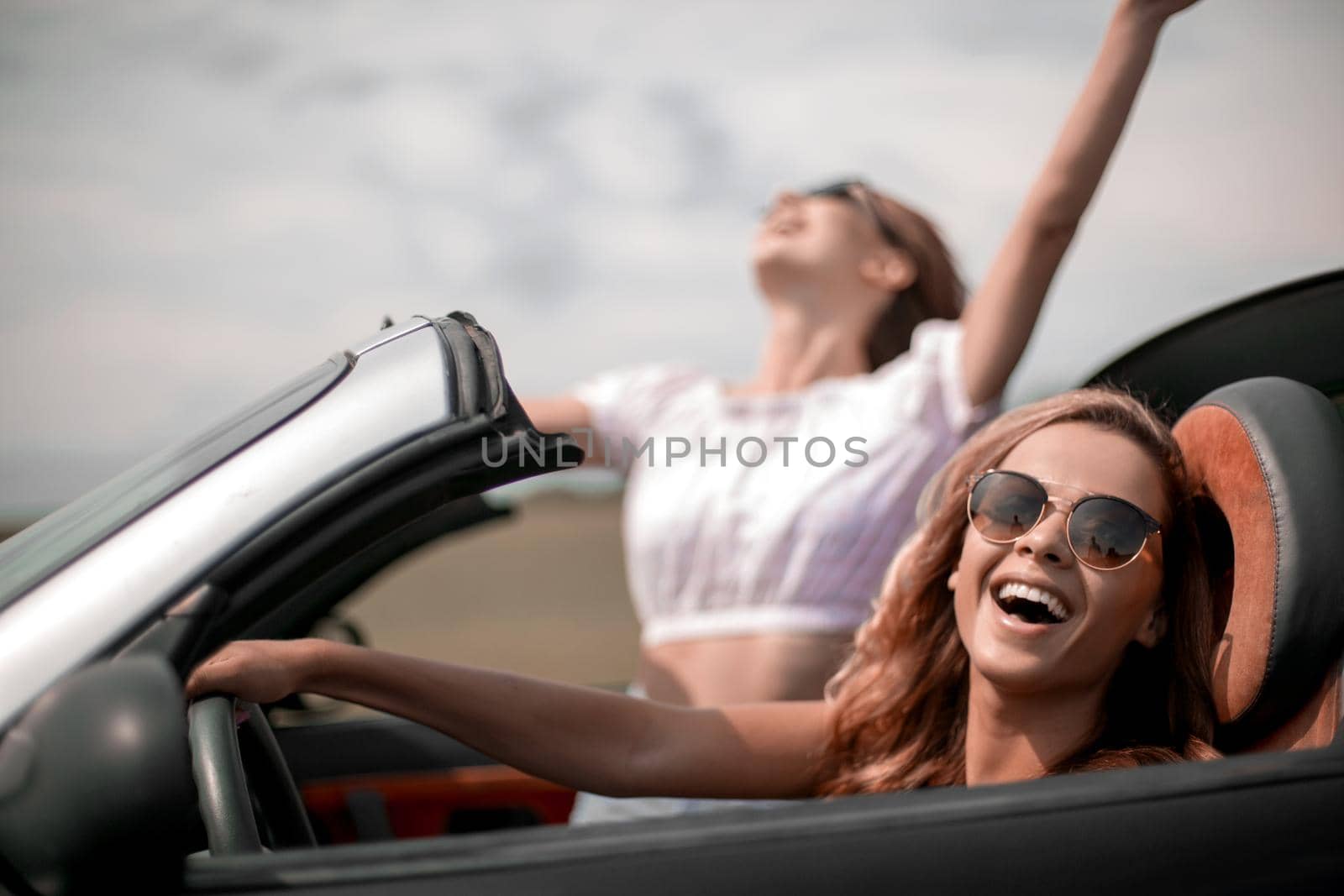 close up.two happy young women in a convertible car by asdf