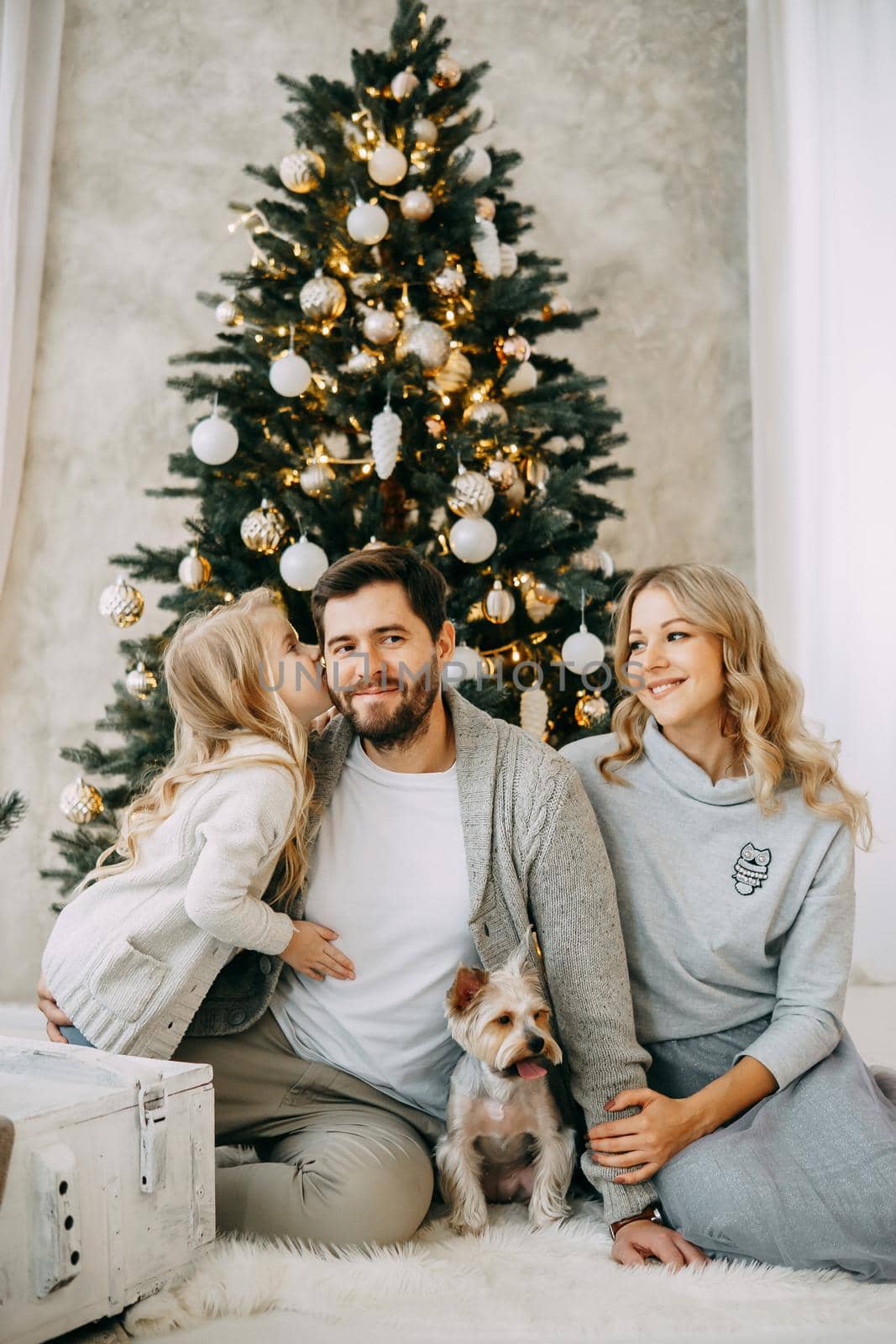 Happy family: mom, dad and pet. Family in a bright New Year's interior with a Christmas tree by Annu1tochka